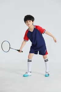 Joven niño asiático en conjunto deportivo transpirable azul y rojo con raqueta