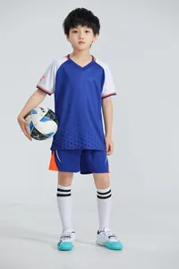 Toma de cuerpo entero de un niño con equipación de fútbol azul transpirable y balón.