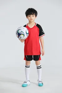 Niño con equipación de fútbol roja y negra y balón, muestra el estilo de entrenamiento.