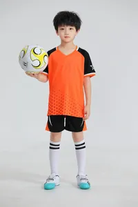 Foto de estudio profesional de un niño posando con un conjunto de fútbol naranja y negro