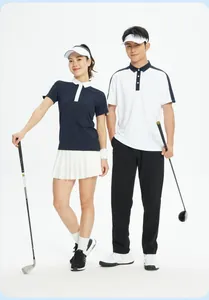 Couple portant des polos de golf color-block et tenant des clubs de golf en studio
