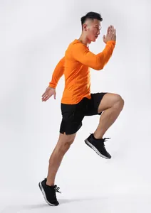Atleta masculino en acción con una camiseta deportiva naranja de manga larga secado rápido.