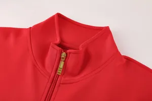Nahaufnahme einer roten Sportjacke mit Stehkragen und hochwertigem Goldreißverschluss
