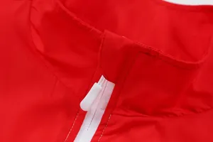 Detailansicht des Stehkragens und des weißen Reißverschlusses einer roten Sportjacke.