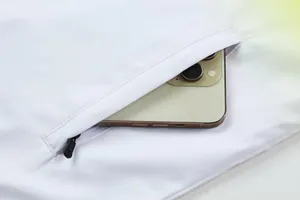 Detailansicht der Reißverschlusstasche einer weißen Sportjacke mit einem Smartphone darin