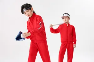 Zwei Kinder in leuchtend roten Trainingsanzügen posieren mit Baseball-Ausrüstung