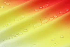 Detailaufnahme eines wasserabweisenden Sportstoffs mit Farbverlauf von Rot nach Gelb