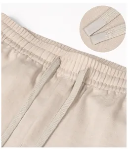 Detail view of beige men's pants showing herringbone fabric and drawstring waistband detail.