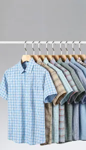 Close-up detail of various 100% cotton short-sleeved plaid shirts on premium wooden hangers