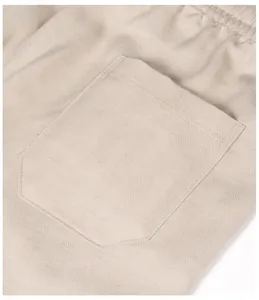 Close-up of beige breathable linen trousers with herringbone texture and pocket