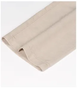 Detail view of breathable beige linen trousers leg cuff with herringbone pattern.
