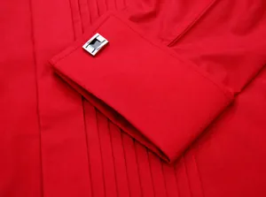 Detailed close-up view of a vibrant red tuxedo shirt cuff with a sleek silver cufflink.