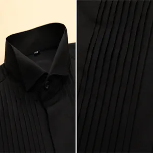 Detailed macro view of the pleated chest and stiff square collar of a black tuxedo shirt.
