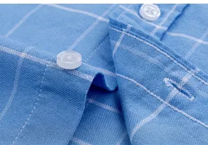Vue rapprochée des boutons nacrés et des coutures sur chemise Oxford à carreaux