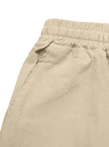 Close-up detail of beige linen casual pants showing elastic waistband and side pocket