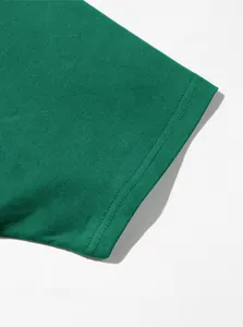 Gros plan détaillé de l'ourlet à double couture sur une manche de t-shirt en coton vert