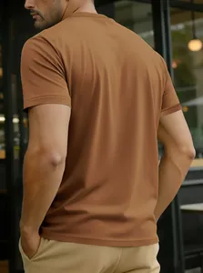 Vue arrière d'un homme portant un t-shirt marron à col rond et manches courtes en extérieur.