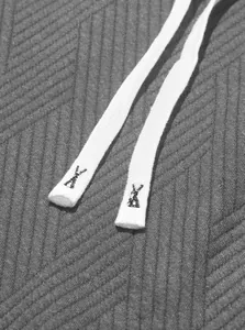 Macro detail of white drawstring tips with embroidery on a textured charcoal grey knit set