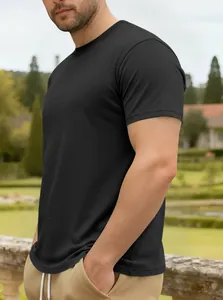 Vue de profil d'un homme portant un t-shirt noir en coton à col rond dans un jardin