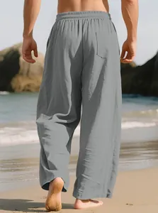 Close-up back view of men's loose grey linen trousers worn at a sunny beach location