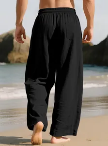 Back view of men's loose black linen trousers on a beach setting