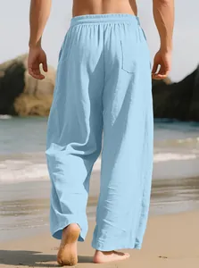 Back view of men's loose light blue linen casual pants on a sunny beach