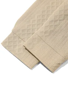 Primer plano del puño de una camisa casual de punto texturizado beige para hombre.