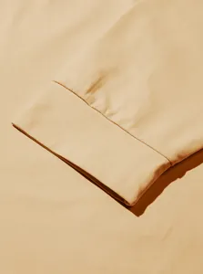 Detailed view of the clean cuff stitching on a soft sand-colored long-sleeve men's hoodie