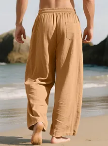 Back view of men's loose khaki linen pants styled for a casual beach walk in daylight.