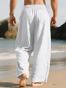 Back view of men's loose white linen casual pants showing pocket detail on beach