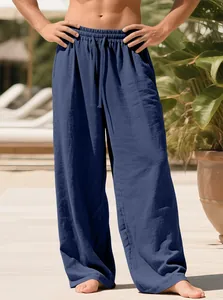 Full view of men's loose navy blue linen drawstring pants on a model in sunlight