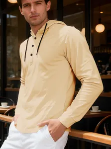 Detail shot of light yellow long sleeve hooded Henley shirt for men on a sunny patio