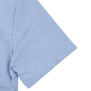 Close-up of light blue linen shirt sleeve showing detailed fabric texture and stitching.