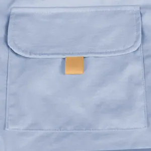 Detailed macro view of a functional pocket on men's light blue cargo shorts with tan pull tab