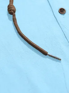 Dettaglio di una camicia in cotone azzurro con coulisse marrone e punta in metallo