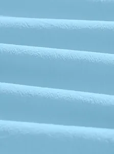 Macro dettaglio di tessuto in puro cotone azzurro che mostra la trama morbida e la qualità