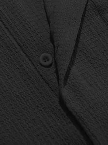 Detailed close-up of black textured fabric and button on a men's business casual shirt
