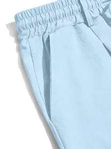 Close-up of light blue cotton linen shorts showing elastic waistband and pocket stitching.