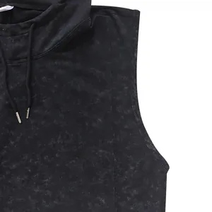 Close-up of black mottled sleeveless hoodie showing drawstring and fabric texture detail.
