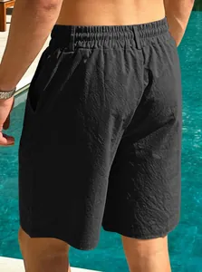 Back view detail of men's quick-dry black beach shorts by a sunny swimming pool