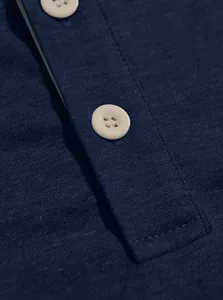 Macro detail of a navy blue Henley shirt placket with white buttons and stitching