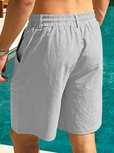 Back view of men's grey cotton linen beach shorts with elastic waist by the pool.