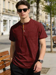 Man wearing a maroon short-sleeved Henley shirt with pocket in a sunny outdoor street setting.