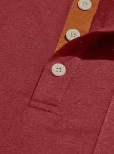 Close-up of men's polo shirt placket with white buttons and contrast orange trim