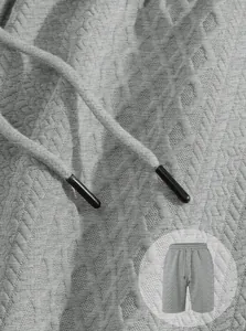 Macro view of jacquard fabric texture and drawstring tips on grey men's casual sports shorts.