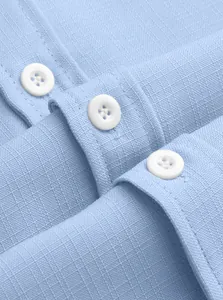 Close-up of light blue linen-textured fabric and white buttons on a men's casual shirt