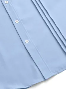 Close-up detail of light blue men's shirt showing white buttons and pleated fabric texture