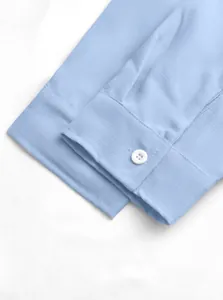 Close-up detail of light blue men's breathable shirt cuff with linen texture and white button