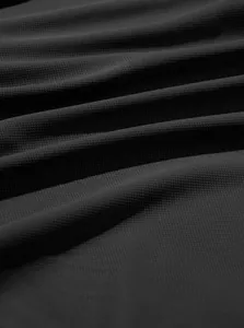 Macro detail showing the intricate black pineapple grid fabric texture on a men's Polo shirt