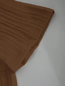 Close-up detail showing the plisse fabric texture of a brown men's short sleeve shirt